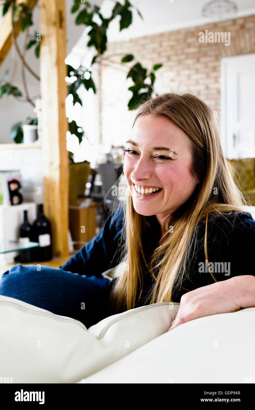 Mitte Erwachsene Frau stÃ¼tzende Sofa Lächeln Stockfoto