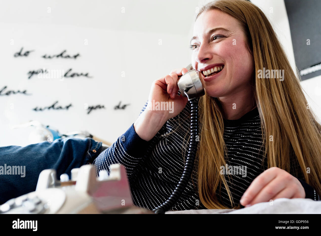 Mitte Erwachsene Frau liegend auf dem Bett am Festnetz-Telefon sprechen Stockfoto