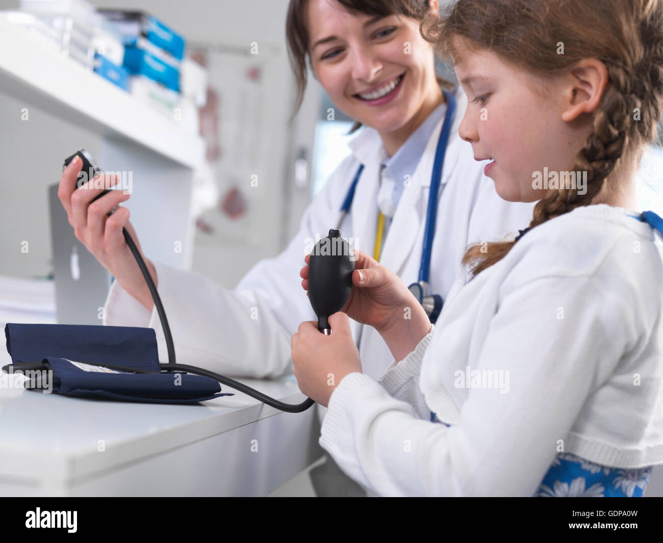 Mädchen mit Blick auf Blutdruckmanschette Arzt Stockfoto