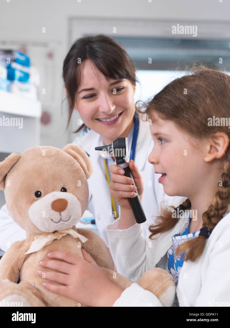 Mädchen mit Otoskop Teddybär prüfen Stockfoto