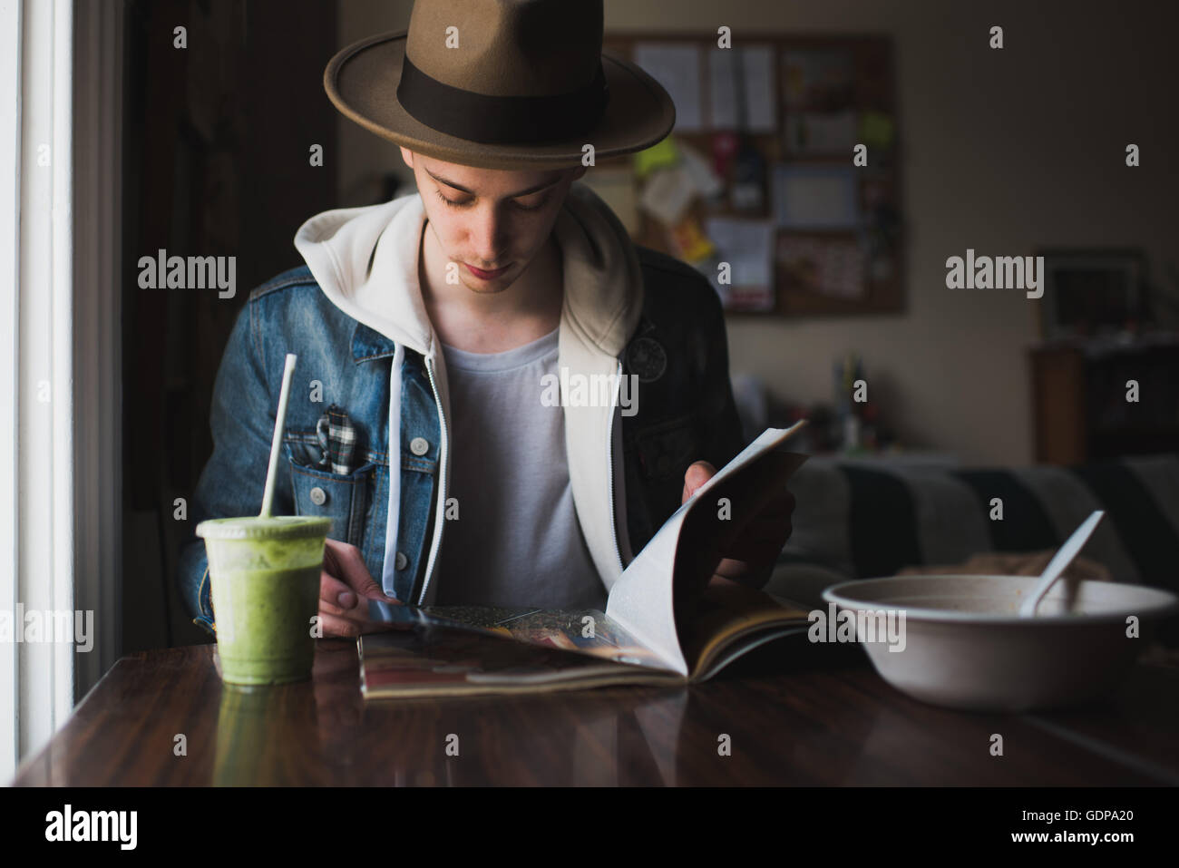 Junger Mann am Tisch sitzen, Essen, lesen Magazin Stockfoto