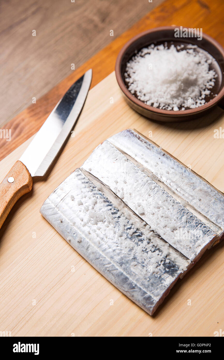 Stück von frischem rohem Delfins Fisch / Cutlassfish, Salz und ein Messer auf Schneidebrett Stockfoto