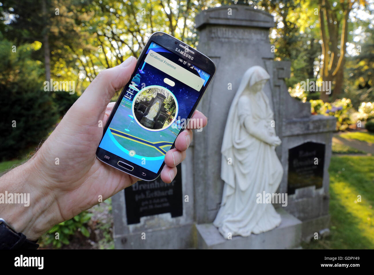 Pokémon Go-Spieler mit seinem Handy auf dem Friedhof in Dortmund, Deutschland Stockfoto