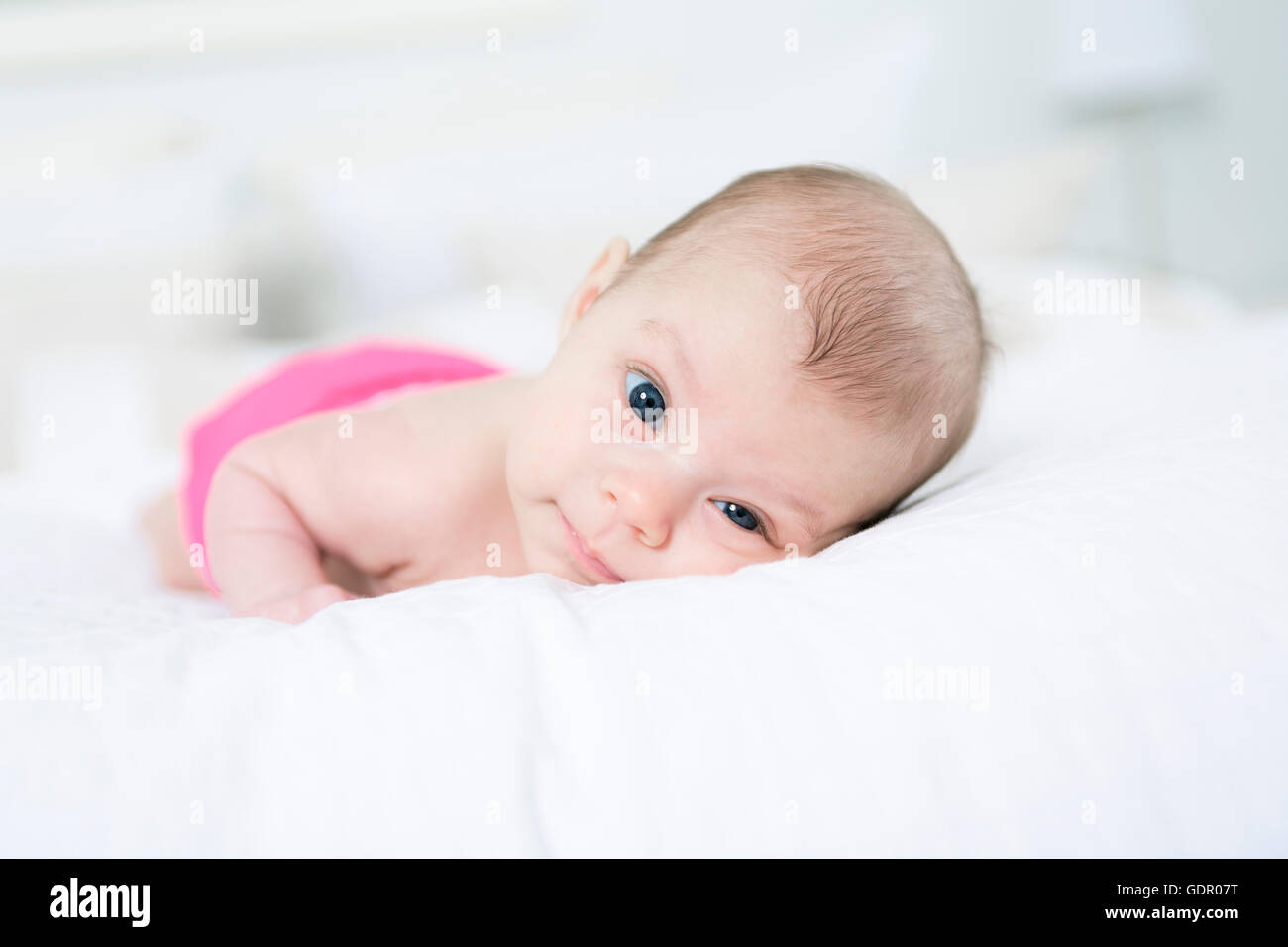 niedliche zwei Monate altes Mädchen im Bett liegend Stockfoto