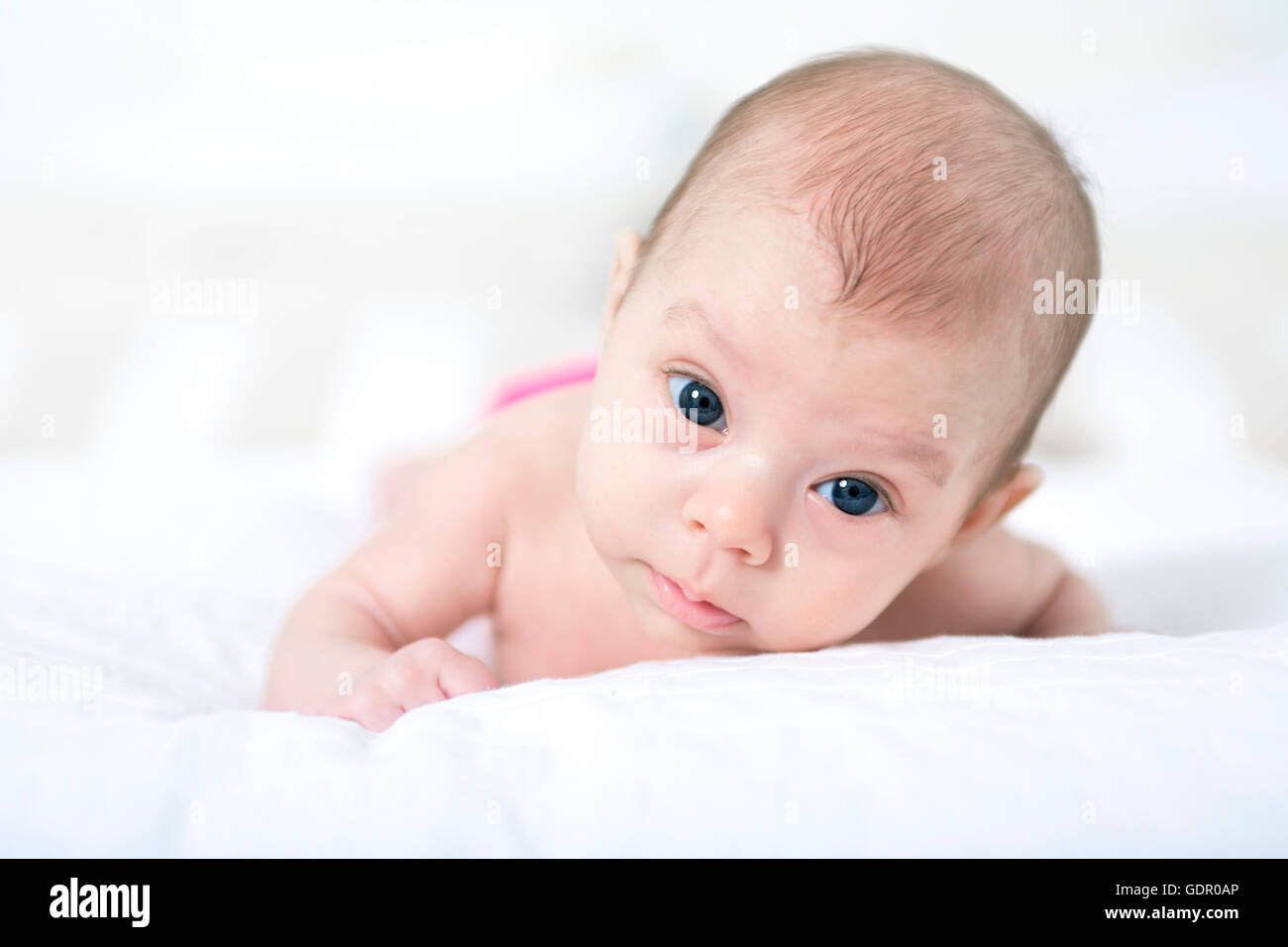 niedliche zwei Monate altes Mädchen im Bett liegend Stockfoto