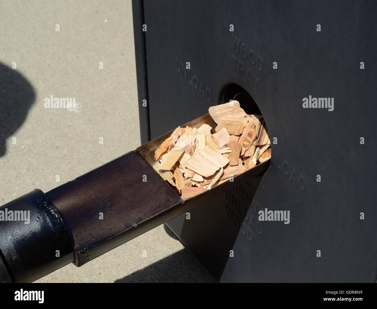 Putting Hickory Holz-Chips in einem Barbecue-Smoker Stockfoto