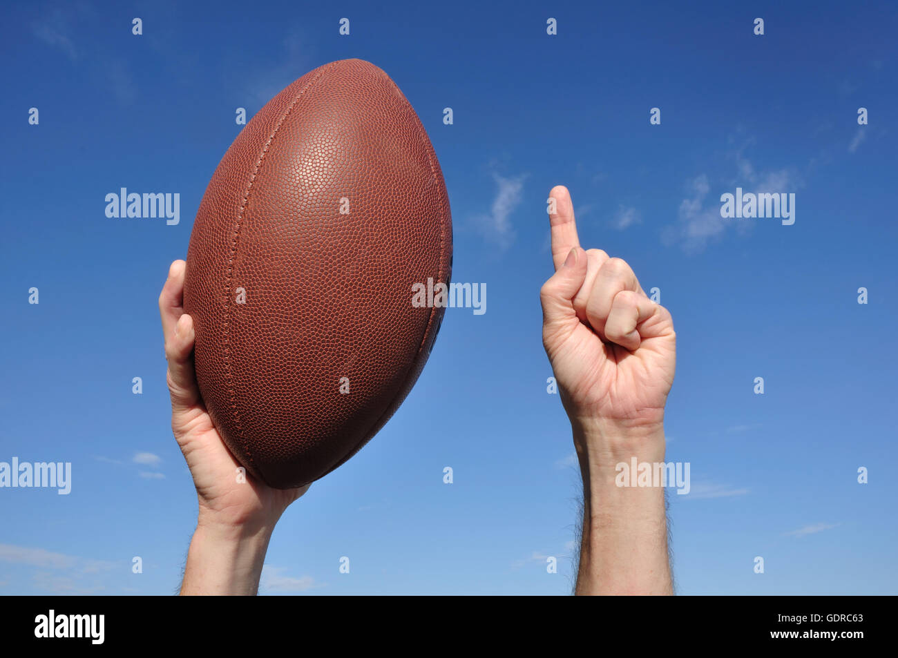 US-amerikanischer Footballspieler feiert einen Touchdown hält ein American Football und geben eine Zahl einen Zeichen Stockfoto
