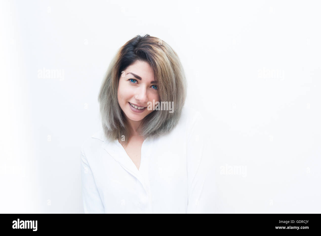 Junge blaue Augen blonde Frau Gesicht lächelnd und einladend, Blick in die Kamera auf weißem Hintergrund Stockfoto