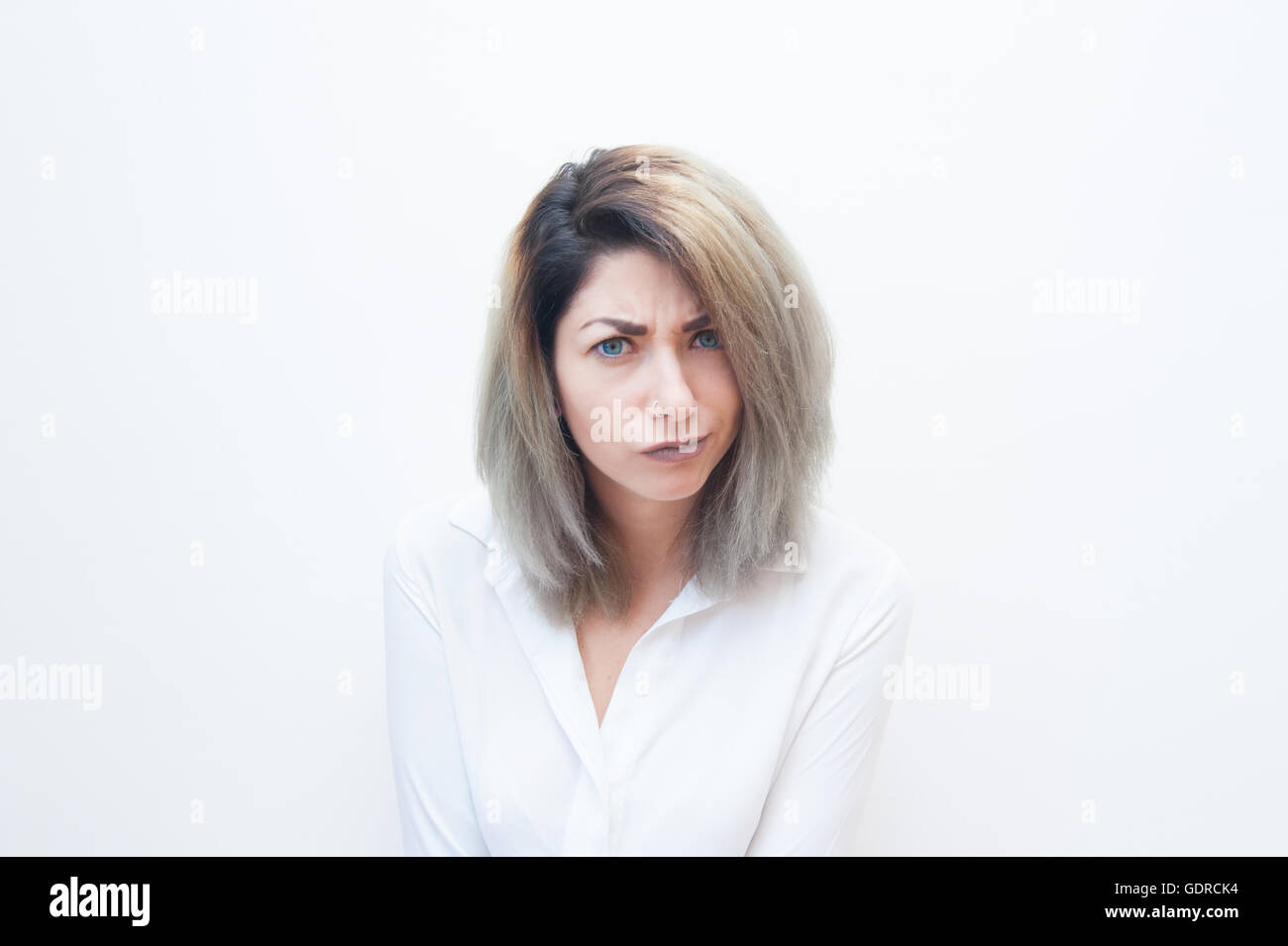 Junge blaue Augen blonde Frau zweifelhaft Blick in die Kamera auf weißem Hintergrund Stockfoto