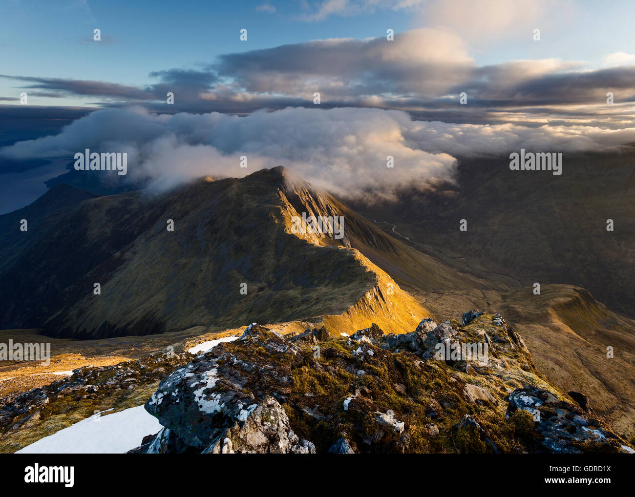 Wolken, die über dem Gipfel eines Seitenlides Sgur nan Saighead, Five Sisters of Kintail, Schottland, bei Sonnenaufgang hereinkommen Stockfoto