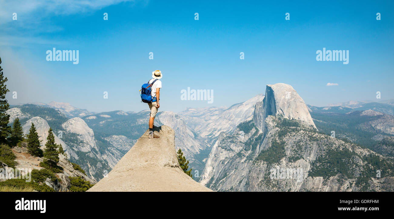 Junger Mann auf Felsvorsprung stehend, mit Blick auf den Half Dome, Blick vom Glacier Point, Yosemite-Nationalpark, Kalifornien, USA Stockfoto