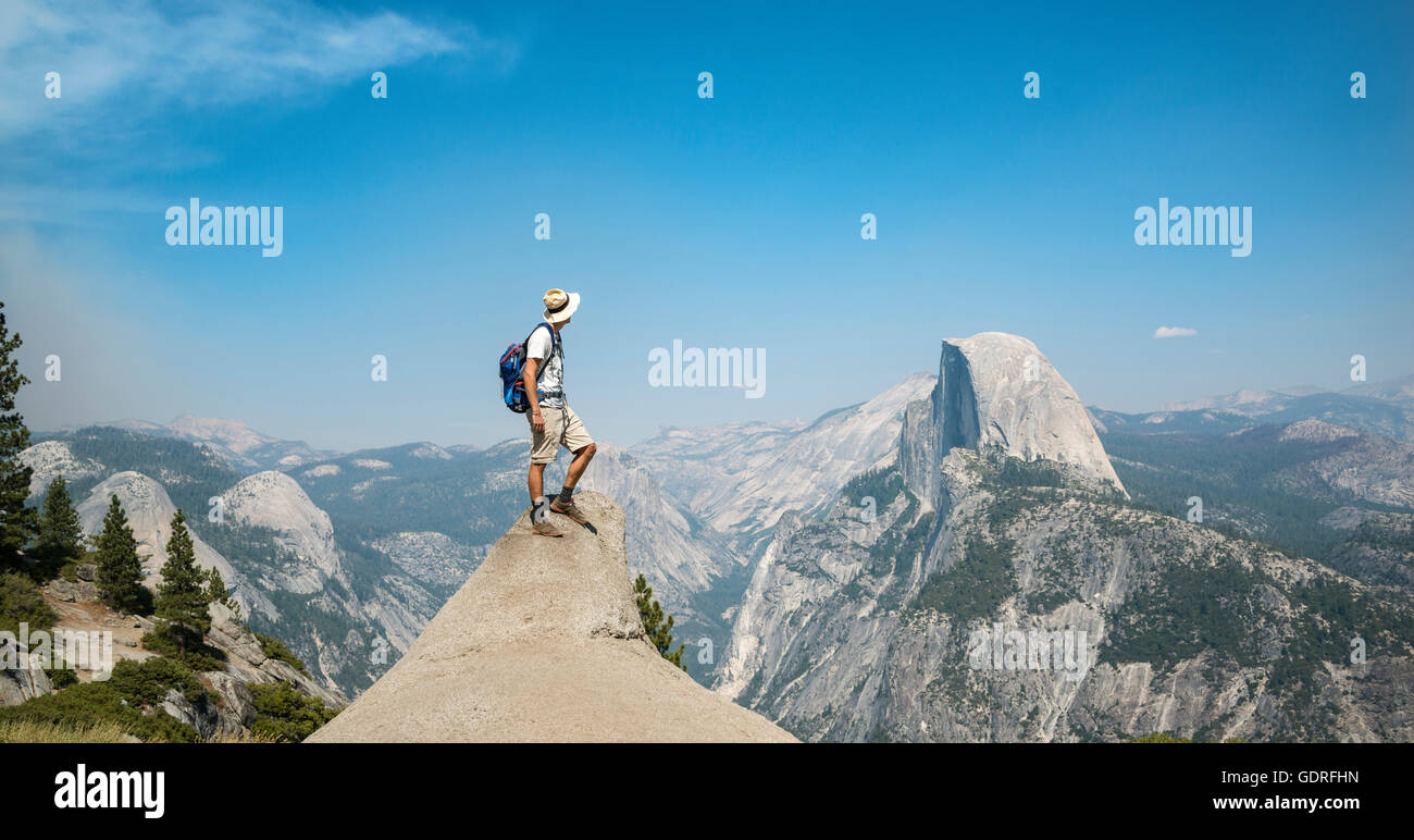 Junger Mann auf Felsvorsprung stehend, mit Blick auf den Half Dome, Blick vom Glacier Point, Yosemite-Nationalpark, Kalifornien, USA Stockfoto