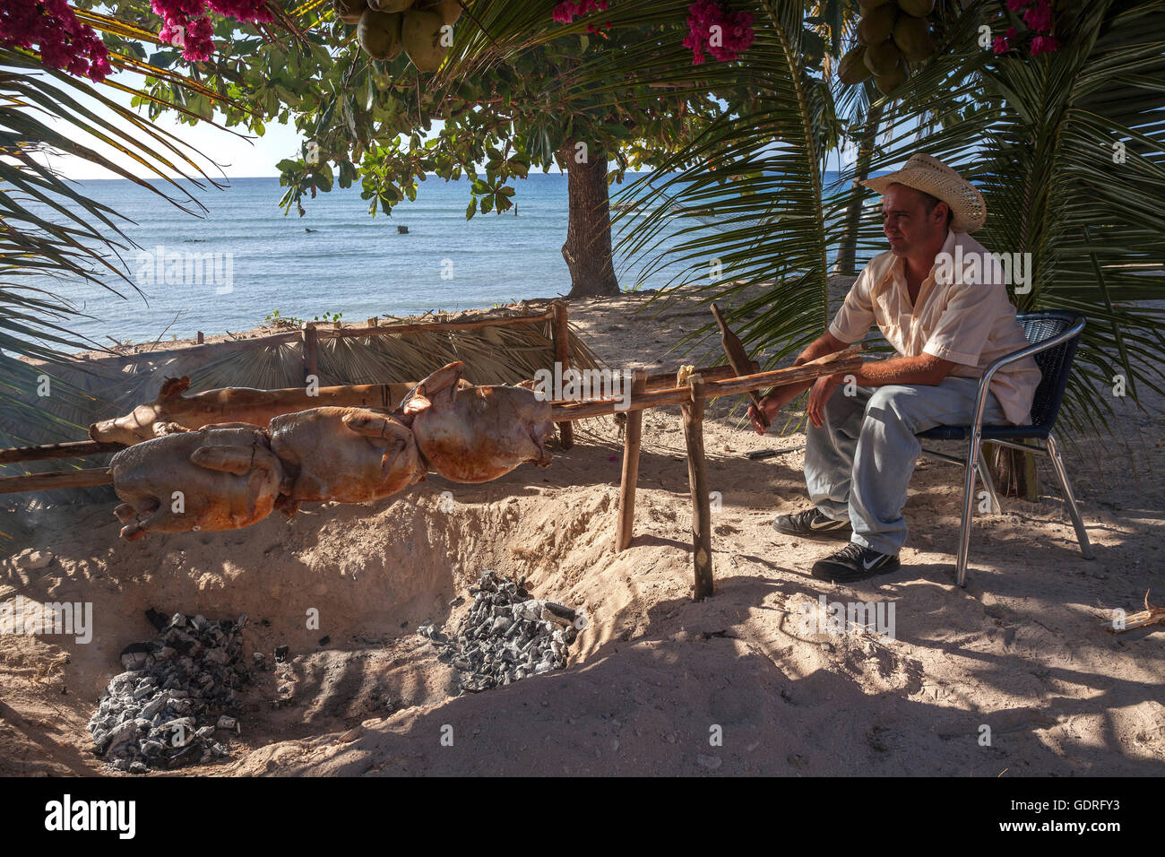 Kubanische Mann Puten Grillen und Spanferkel am Strand von Playa Ancon, in der Nähe von Trinidad, Provinz Sancti Spiritus, Kuba Stockfoto