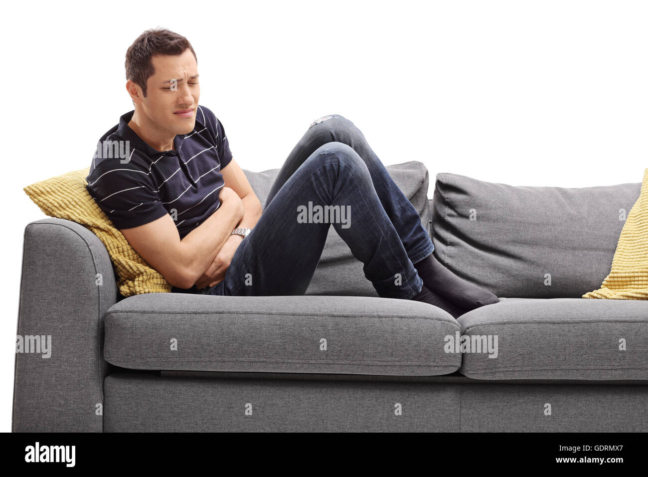 Junger Mann auf einem Sofa sitzt und Magen Schmerzen isoliert auf weißem Hintergrund Stockfoto