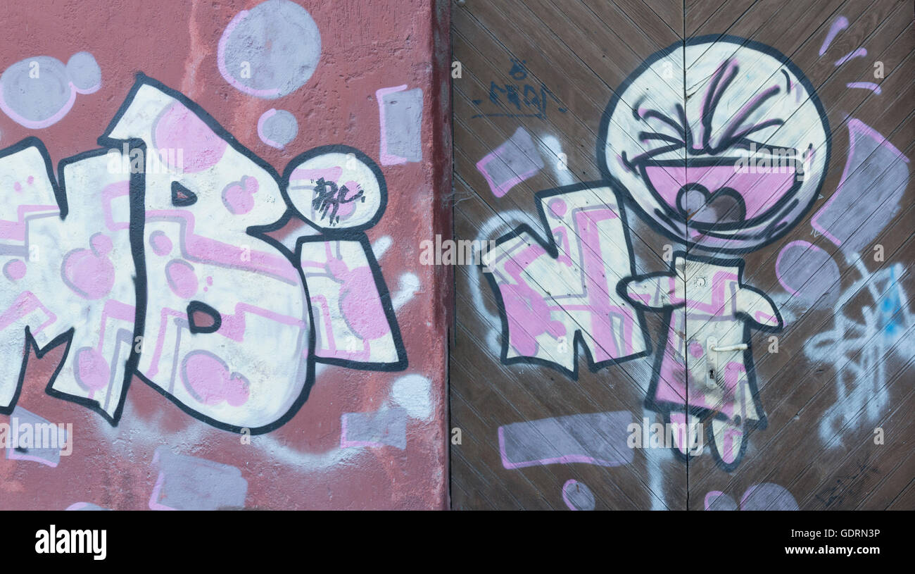 Eine leistungsstarke einfache Graffiti-Kunstwerk, bekannt als "Bambin", die über eine, Cladded Wand gesprüht wird und eine große Holztür. Stockfoto Eine leistungsstarke einfache Graffiti-Kunstwerk, bekannt als "Bambin", die über eine, Cladded Wand gesprüht wird und eine große Holztür. Stockfoto