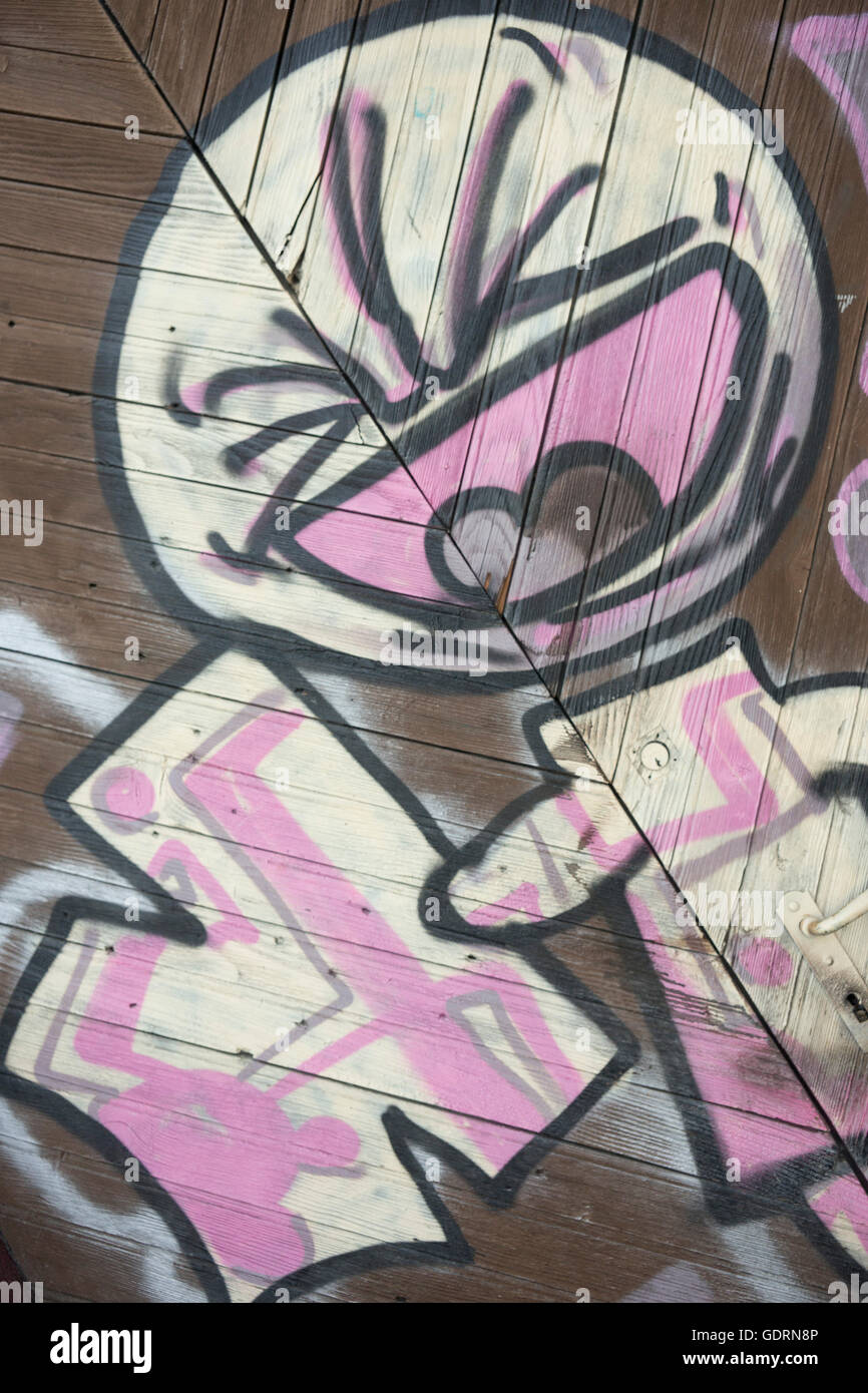 Eine leistungsstarke einfache Graffiti-Kunstwerk, bekannt als "Bambin", die über eine, Cladded Wand gesprüht wird und eine große Holztür. Stockfoto Eine leistungsstarke einfache Graffiti-Kunstwerk, bekannt als "Bambin", die über eine, Cladded Wand gesprüht wird und eine große Holztür. Stockfoto