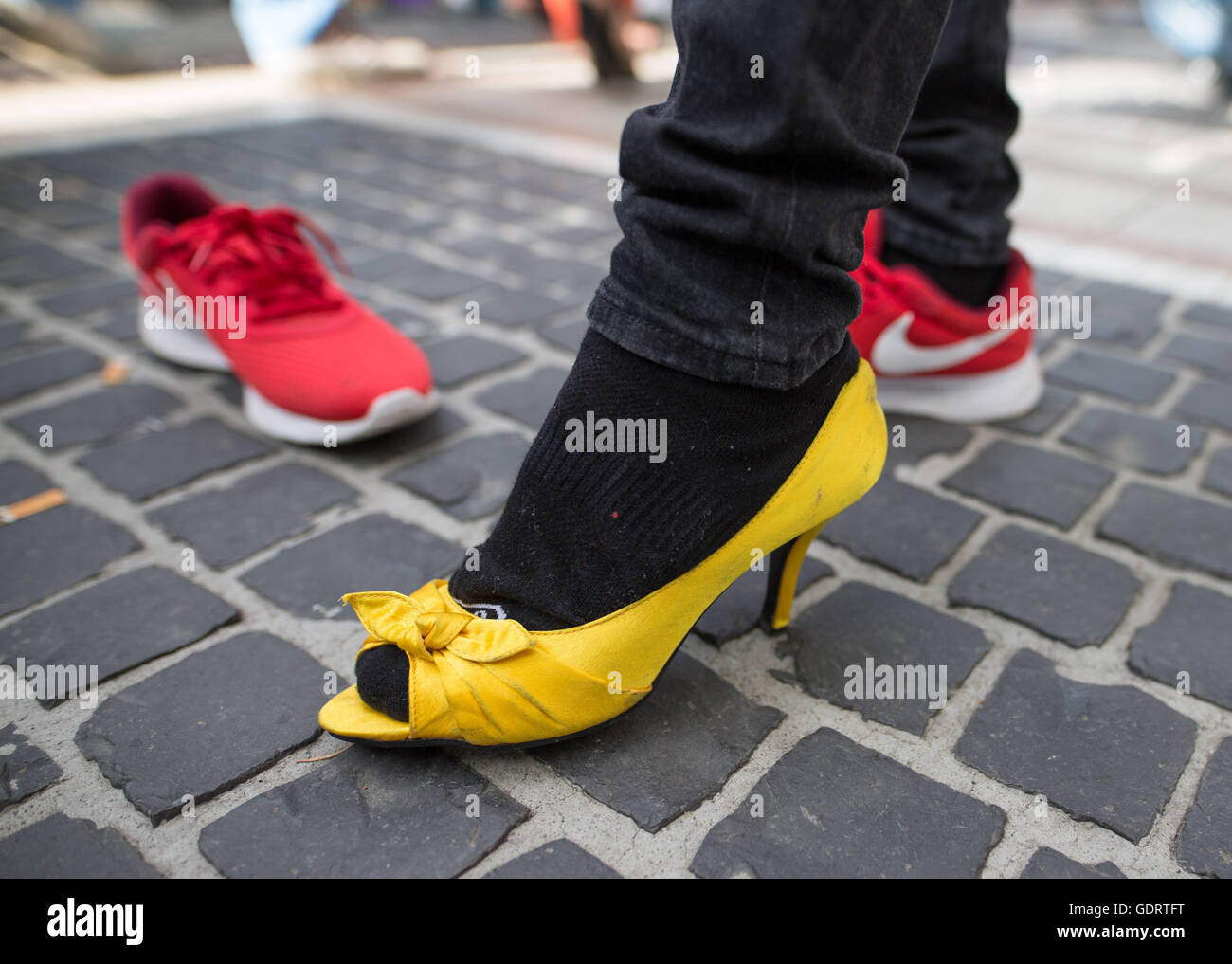 Ein Teilnehmer trägt während des High-Heel-Rennens in Frankfurt Am Main, Deutschland, 16. Juli 2016 gelben zehenoffenen Pumps. Das Rennen fand anlässlich des Christopher Street Day. Foto: Frank Rumpenhorst/dpa Stockfoto