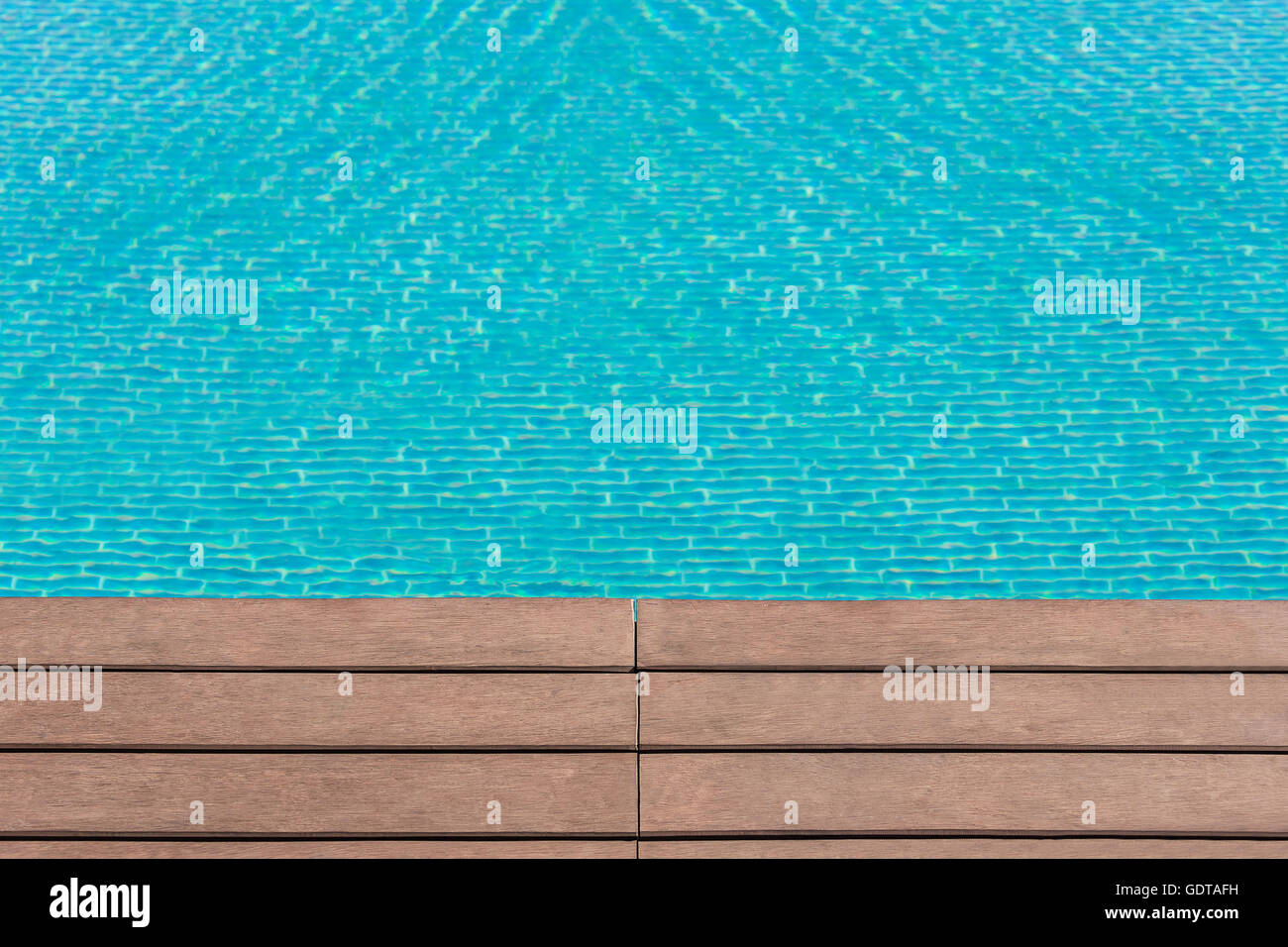 Nahfokus von Rand des künstlichen Holzboden in der Nähe von Schwimmbad mit beweglichen blauen Wasser als unscharfen Hintergrund Stockfoto
