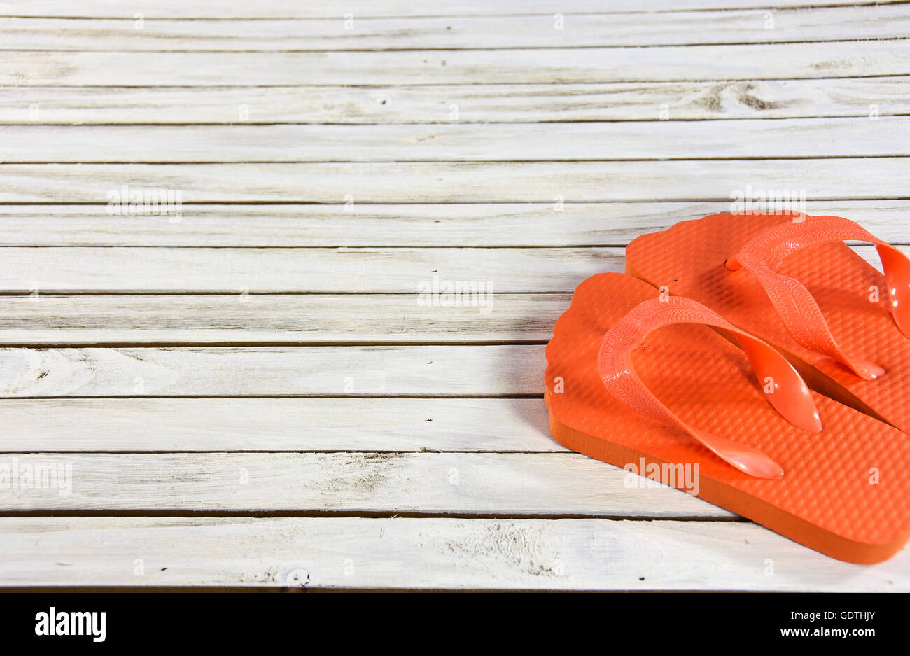 Leuchtend orange Flip-flops auf weiß getünchten Holz. Stockfoto