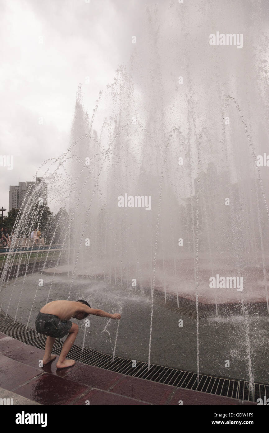 Ein junge Spiel mit Wasser an einem Brunnen in den Platz des Volkes in Shanghai Stockfoto