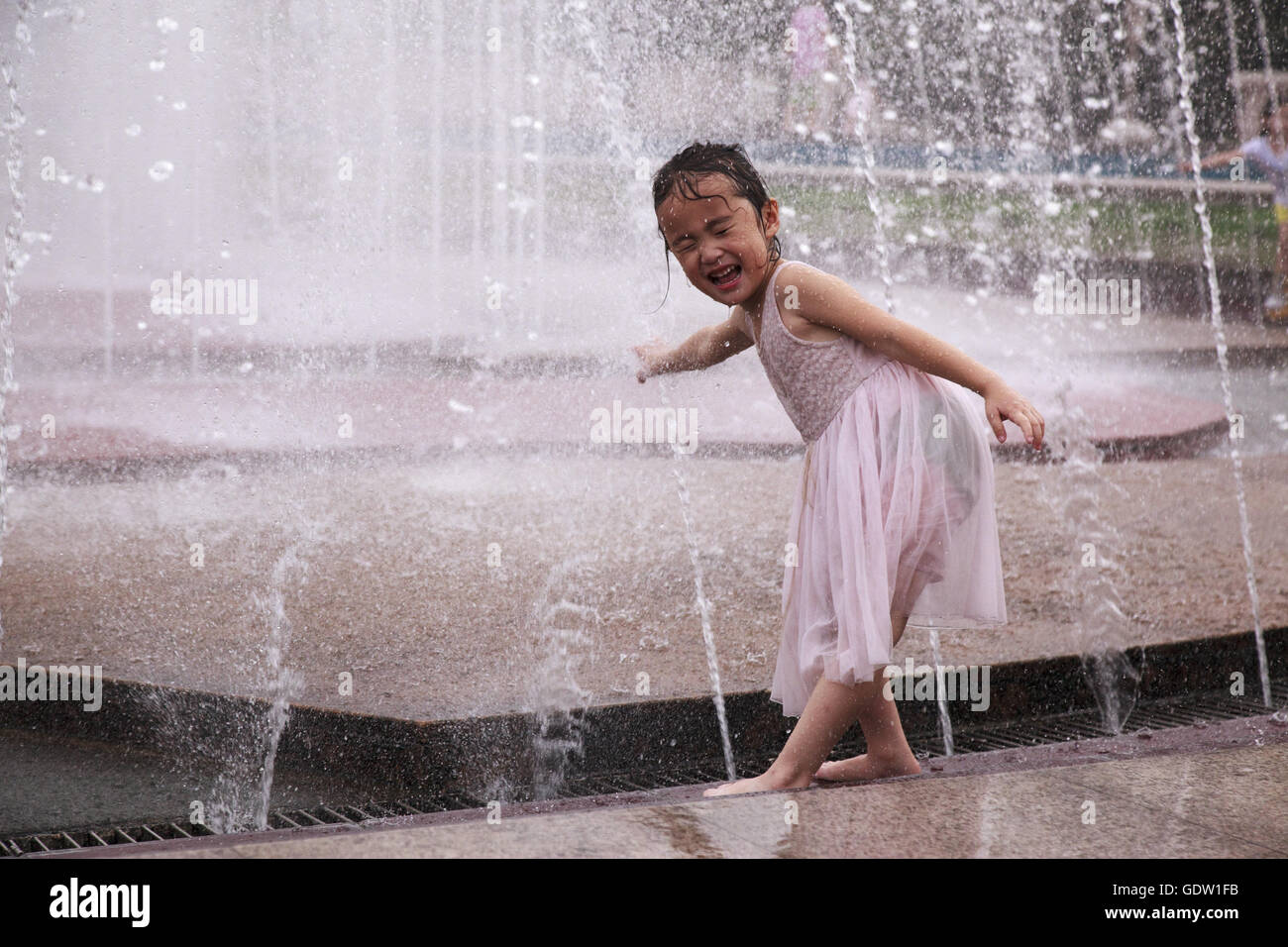 Ein Mädchen spielen mit Wasser an einem Brunnen in den Platz des Volkes in Shanghai Stockfoto