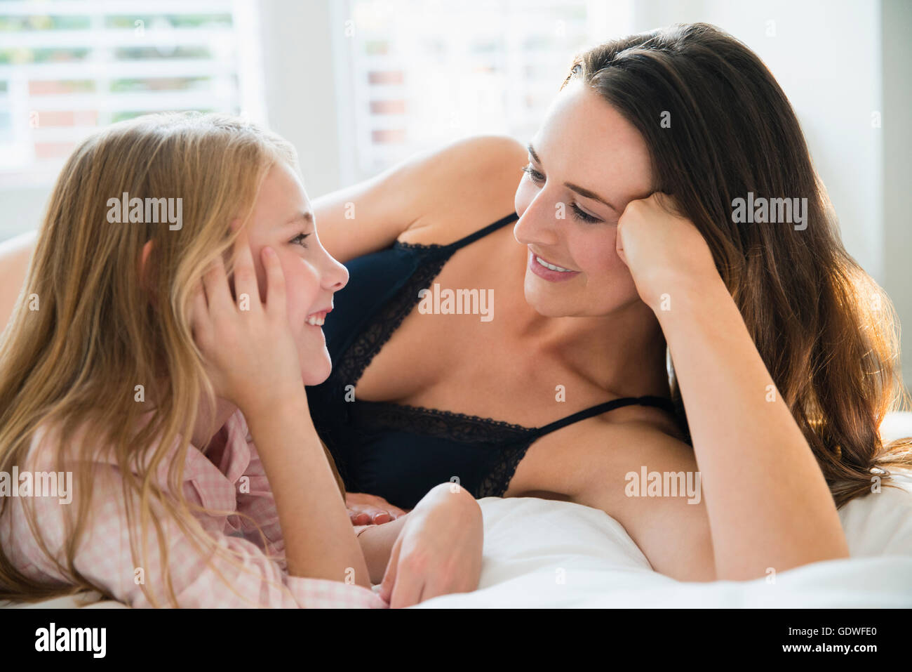 Mutter und Tochter Handauflegen Bett sprechen Stockfoto