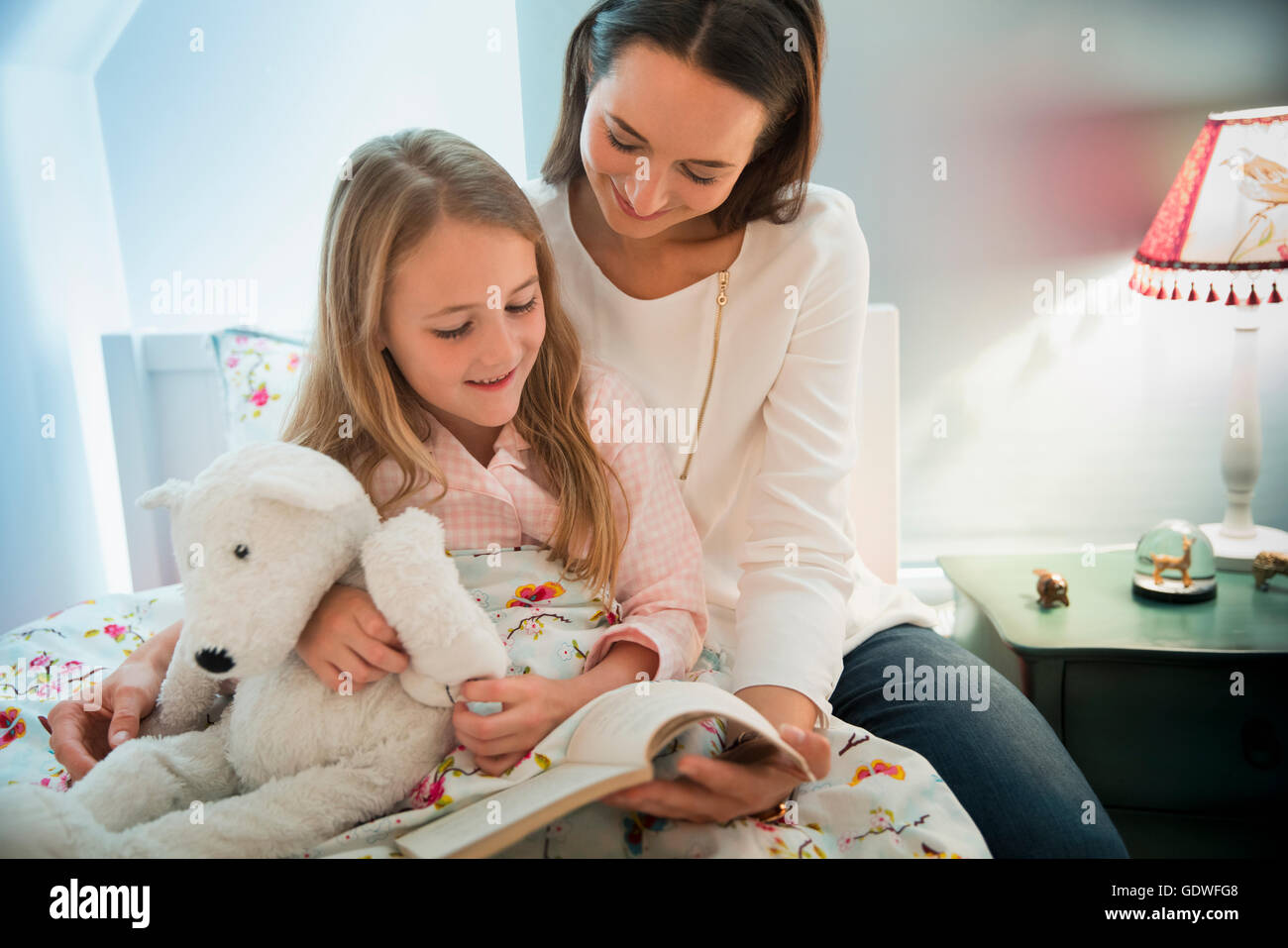 Mutter Lesung Gutenachtgeschichte mit Tochter im Bett Stockfoto