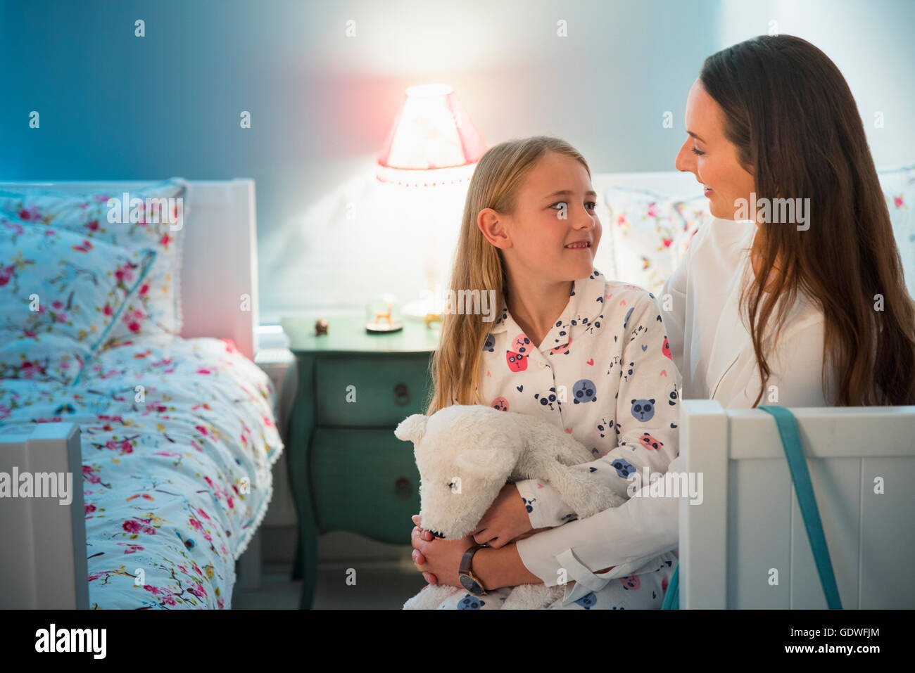 Mutter und Tochter sprechen vor dem Schlafengehen im Schlafzimmer Stockfoto