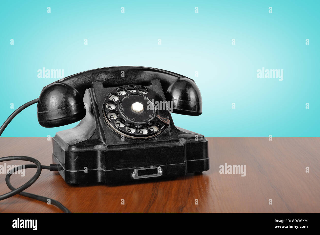 Vintage-Handys - schwarze Retro-Telefon auf einem Holztisch und einen blauen Hintergrund. Stockfoto