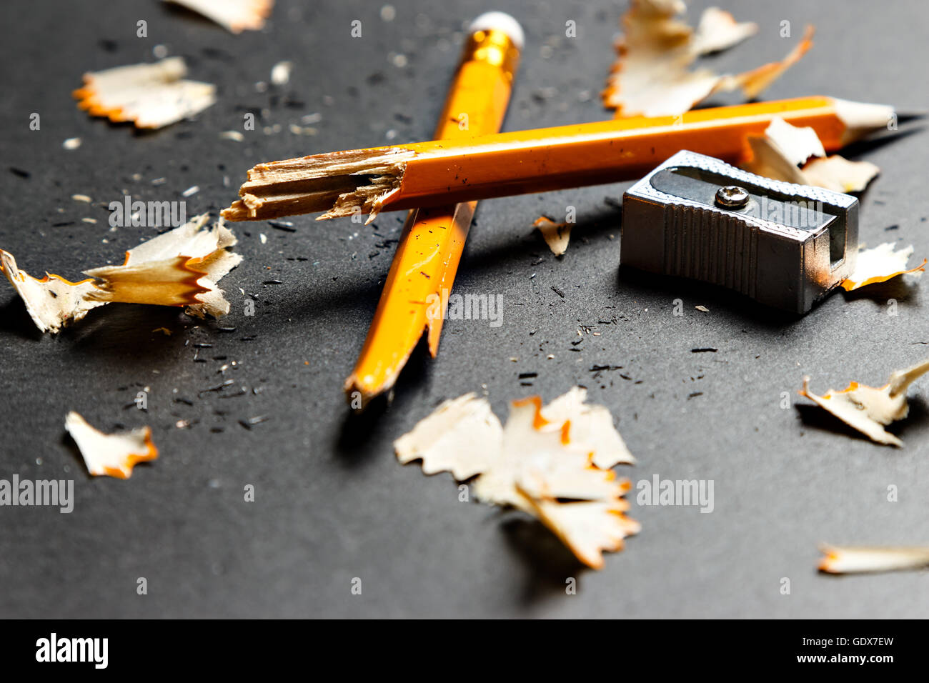 Gebrochene Bleistift mit Metall Spitzer und Späne auf schwarzem Hintergrund. Horizontales Bild. Stockfoto