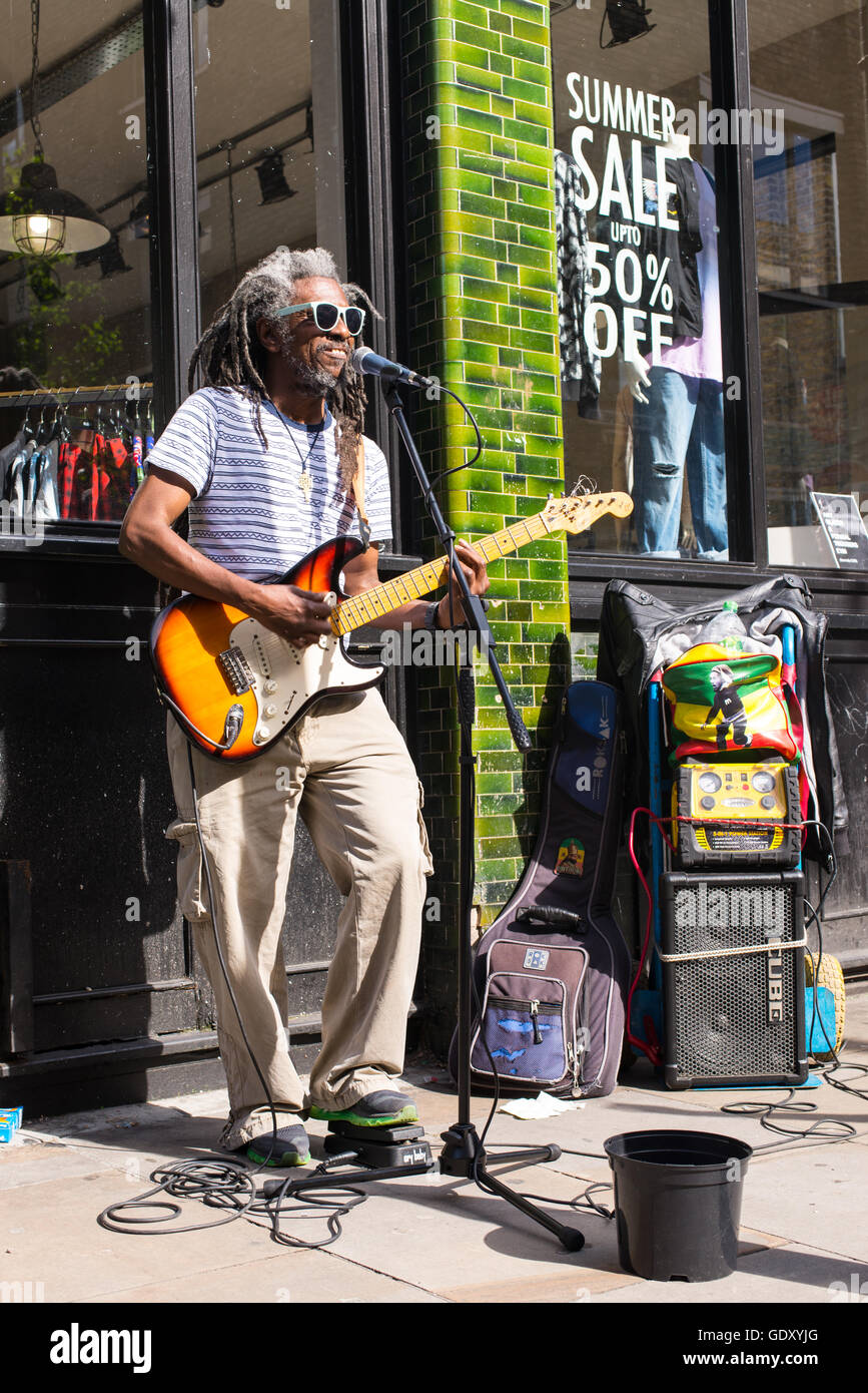 Busker Musiker Künstler mit Afro style dreadlocks Haar spielen, E-Gitarre und Gesang in Brick Lane Stockfoto