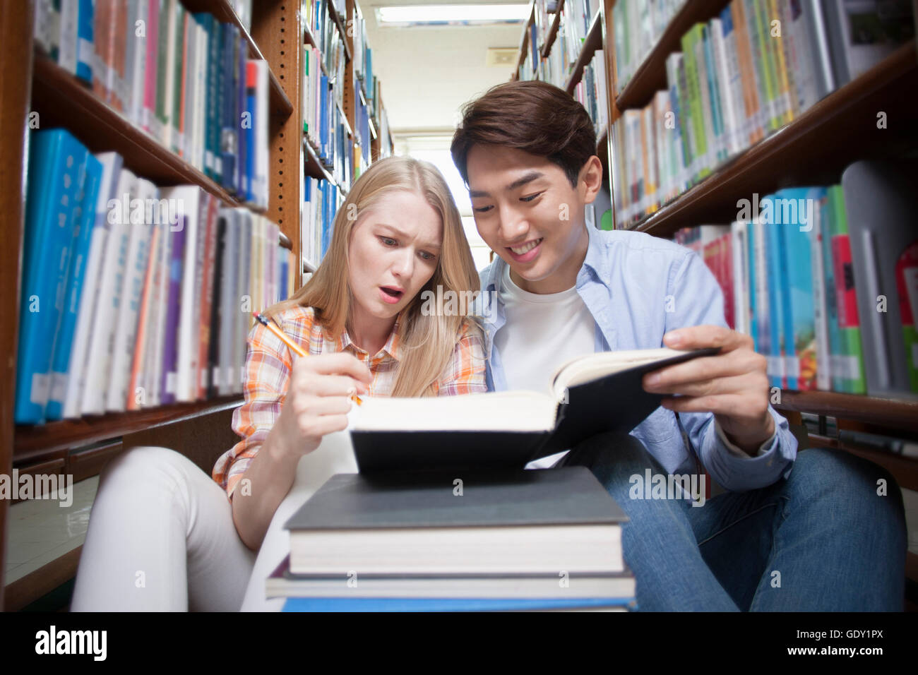 Zwei College-Studenten, die ein Buch in Bibliothek lächelnd Stockfoto