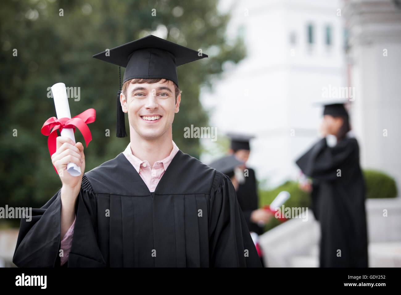 Porträt des jungen lächelnd männliche College-Absolvent mit Diplom Stockfoto