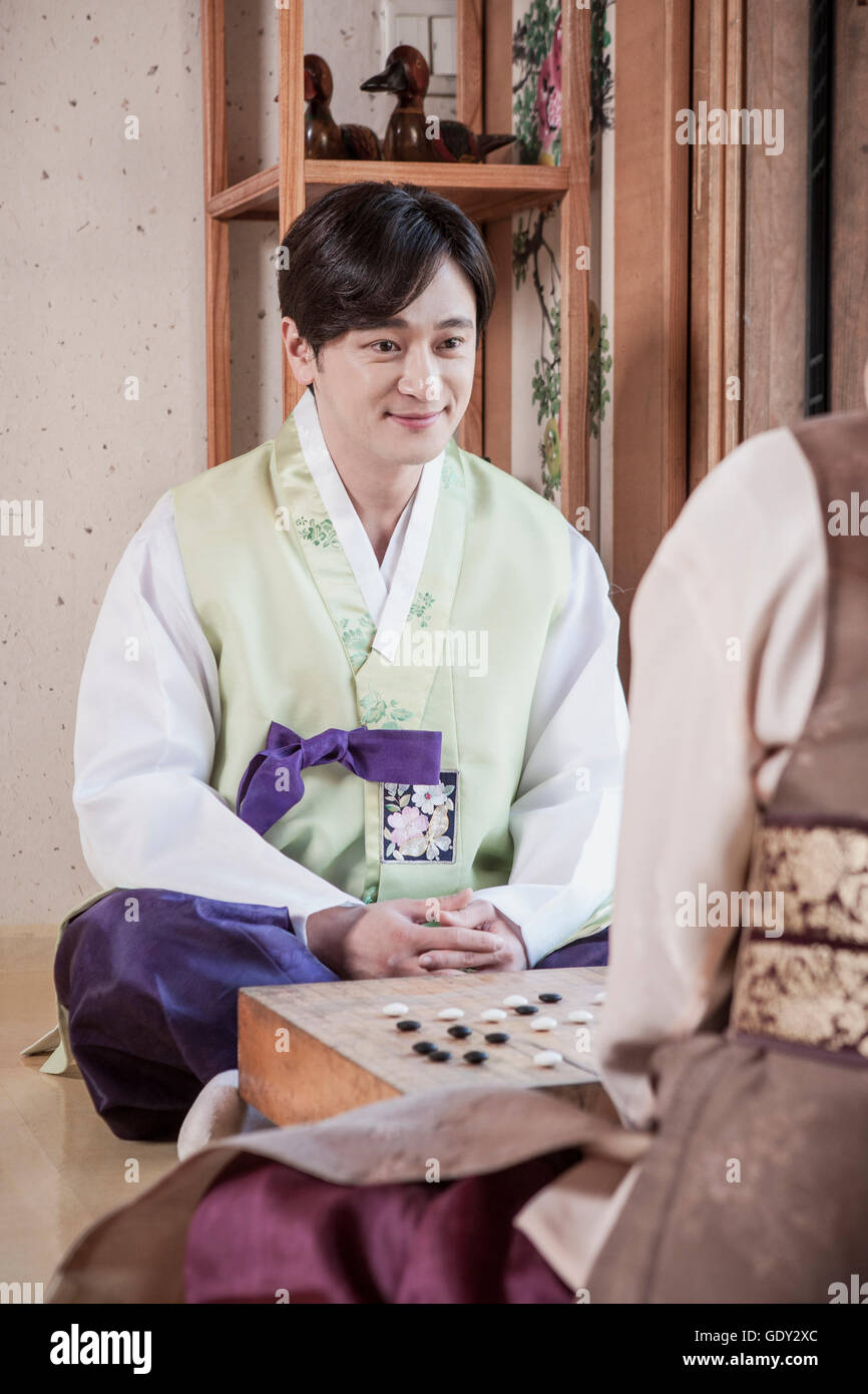 Jungen Mann in traditionelle koreanische Kleidung spielen Baduk lächelnd Stockfoto