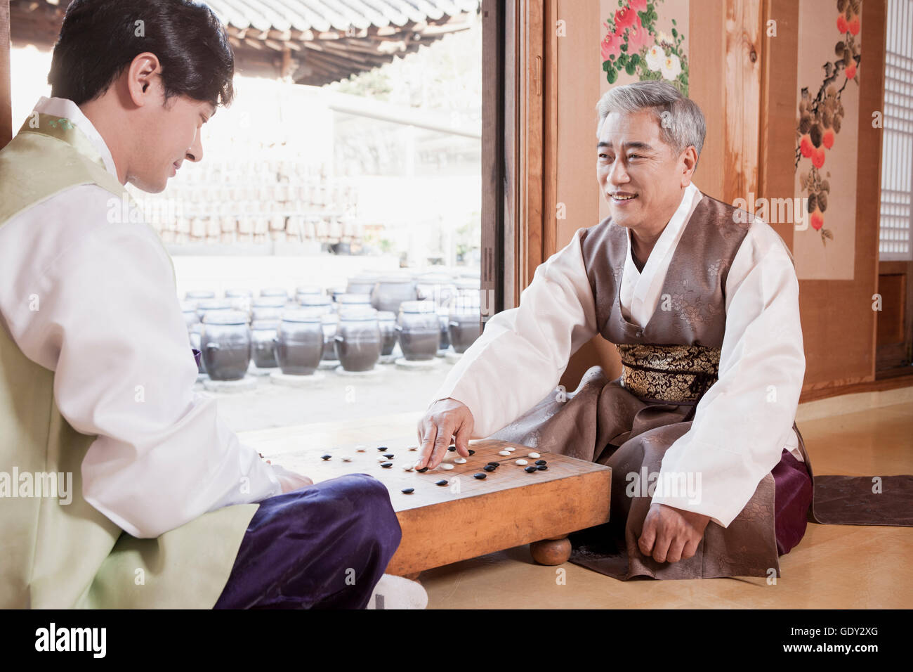 Junger Mann und Greis in traditionelle koreanische Kleidung spielen baduk Stockfoto