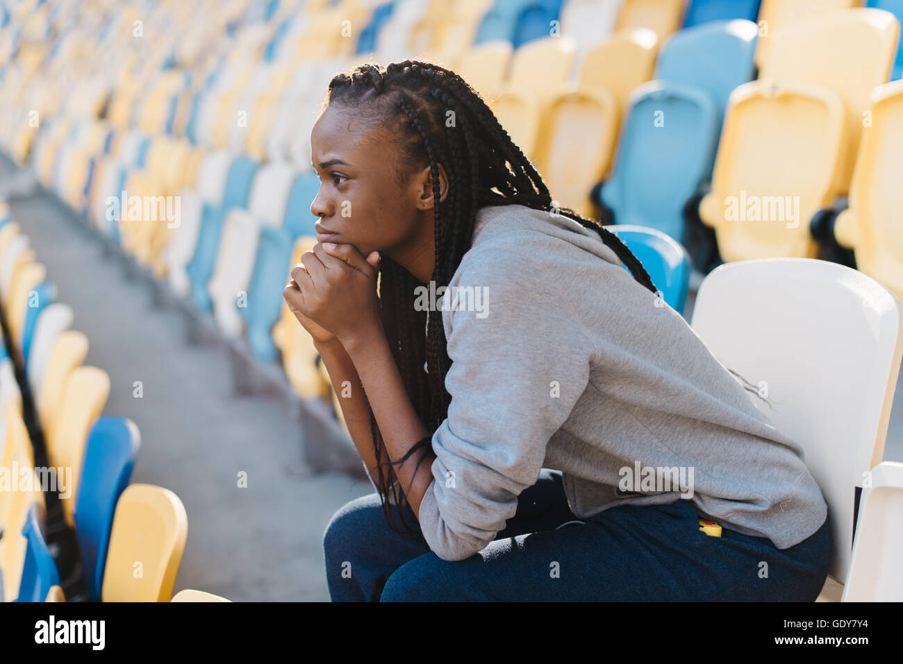 Seitenansicht des afroamerikanischen Frau sitzt mit Kopf auf die Hände und Gefühl enttäuscht gegen Stadion Zeilen Stockfoto