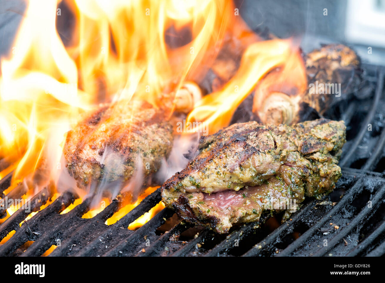 Große Steaks am Grill, Flammen und Rauch steigt vom Grill verbrannt Stockfoto