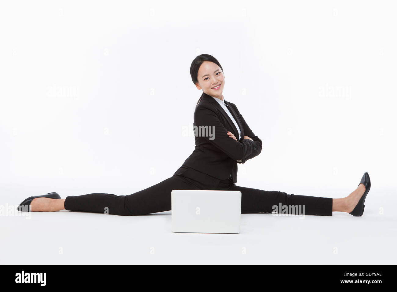 Lächelnde Geschäftsfrau, die ihre Beine Gelenkarme mit einem Notebook-computer Stockfoto