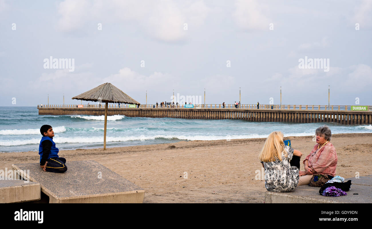 DURBAN, Südafrika - 17. August 2015: Leute sitzen in der Nähe der Pier am Nordstrand auf der Golden Mile Promenade. Stockfoto