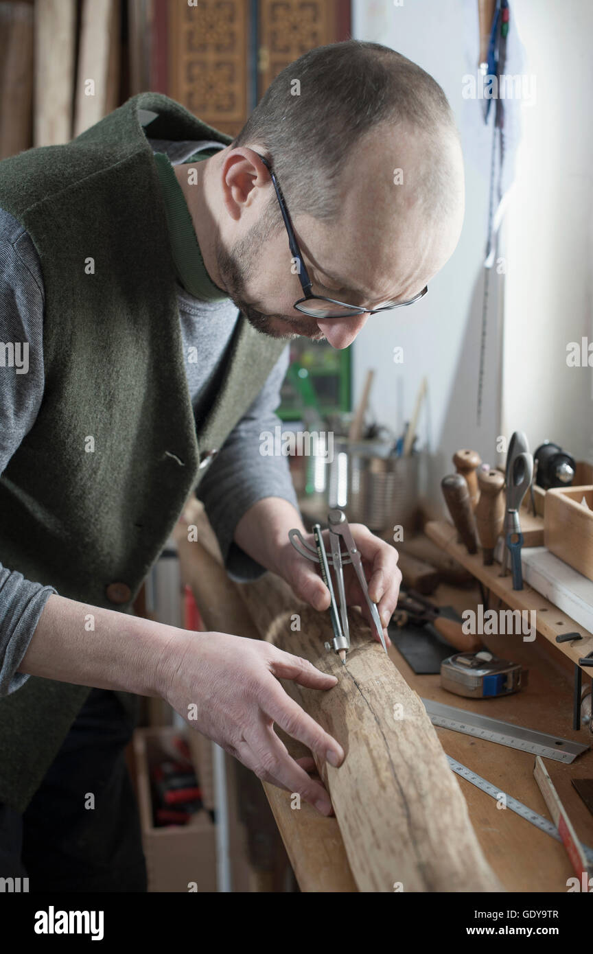 Männliche Bogenmacher markieren auf Holz mit Kompass, Workshop, Bayern, Deutschland Stockfoto