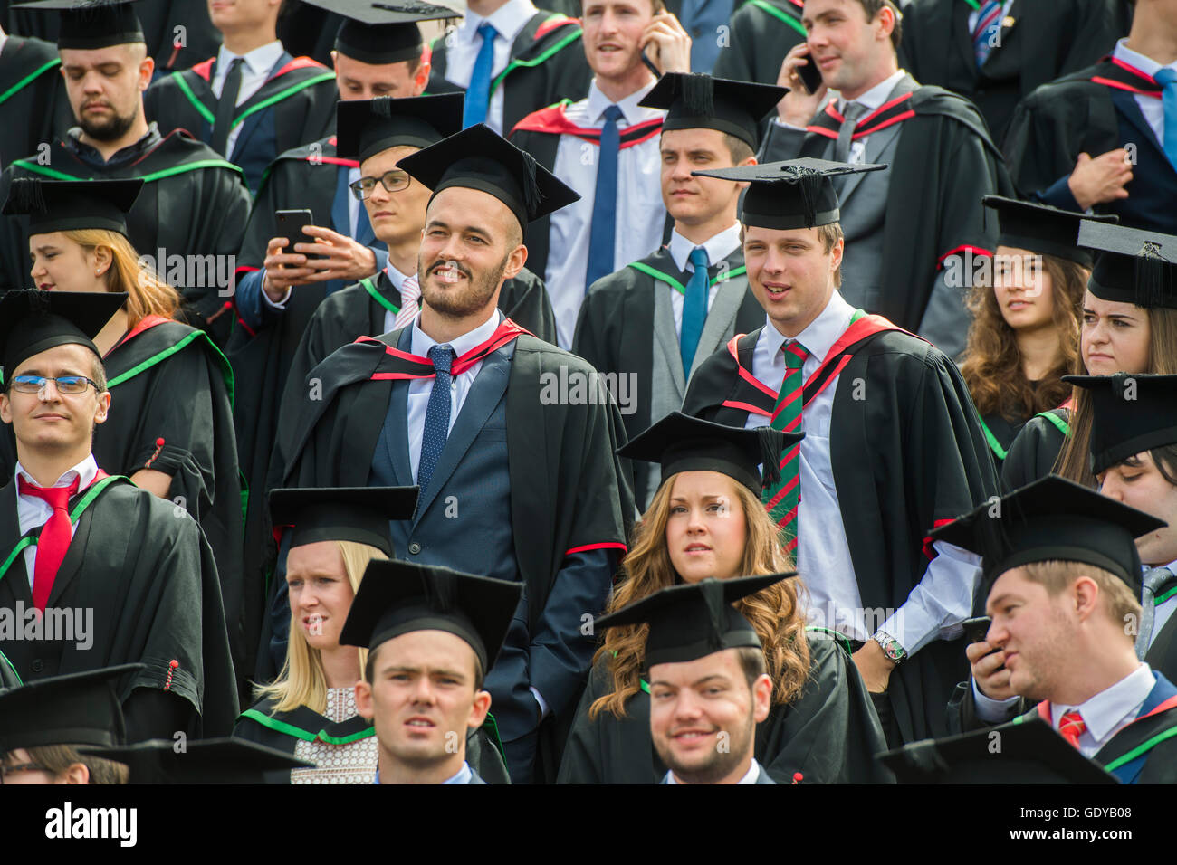 Hochschulbildung in Großbritannien: eine Gruppe von Aberystwyth Universitätsstudenten tragen traditionelle Kleider, Umhänge und Mörtel Boards immer bereit, ihre Gruppe Fotografieren bei ihrer Abschlussfeier Tag Juli 2016 Stockfoto