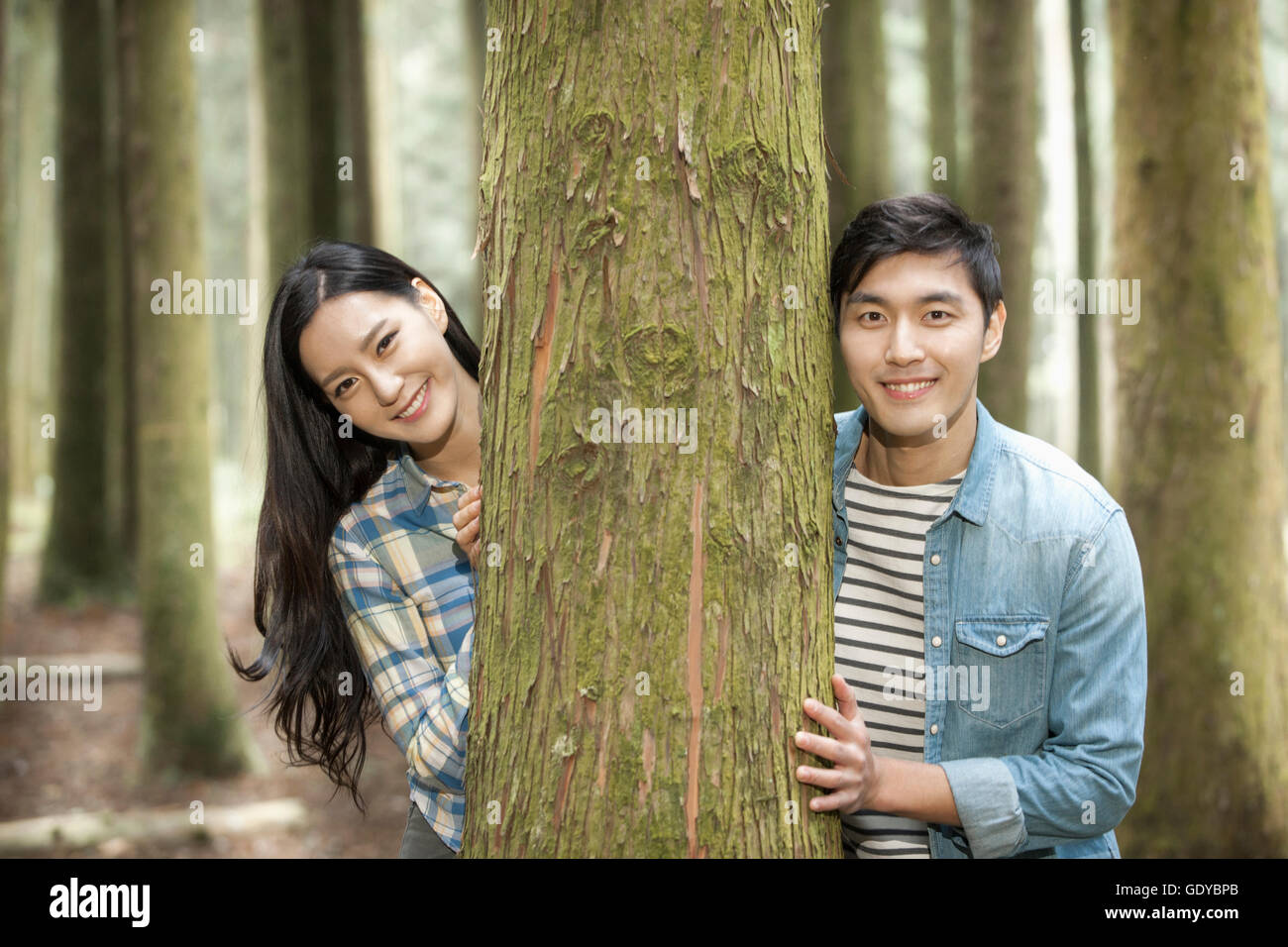 Porträt des jungen lächelnde paar zusammen einen Baum zu berühren Stockfoto