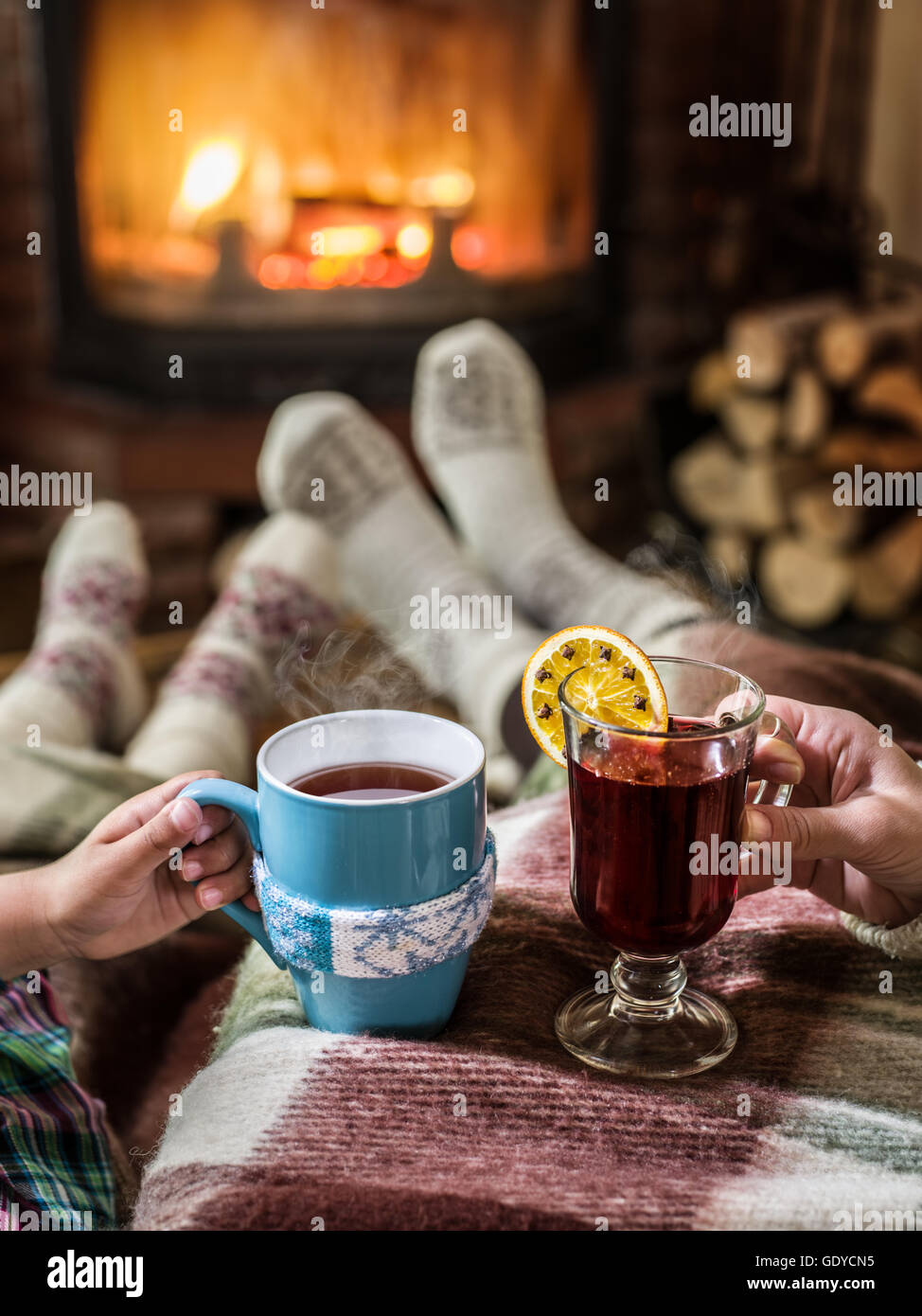 Wärmend und entspannend in der Nähe von Kamin. Frau Füße in der Nähe von der Tasse heißes Getränk am Kamin. Stockfoto