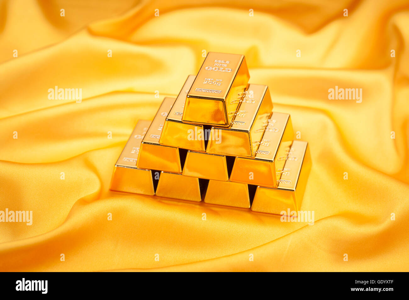 Gestapelte Goldbarren auf gelben Seidentuch Stockfoto