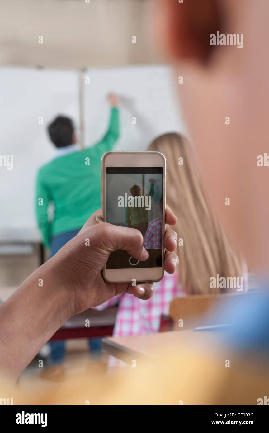 Lehrer Unterricht im Klassenzimmer während des Studiums nehmen sein Bild auf ihrem Smartphone, Bayern, Deutschland Stockfoto