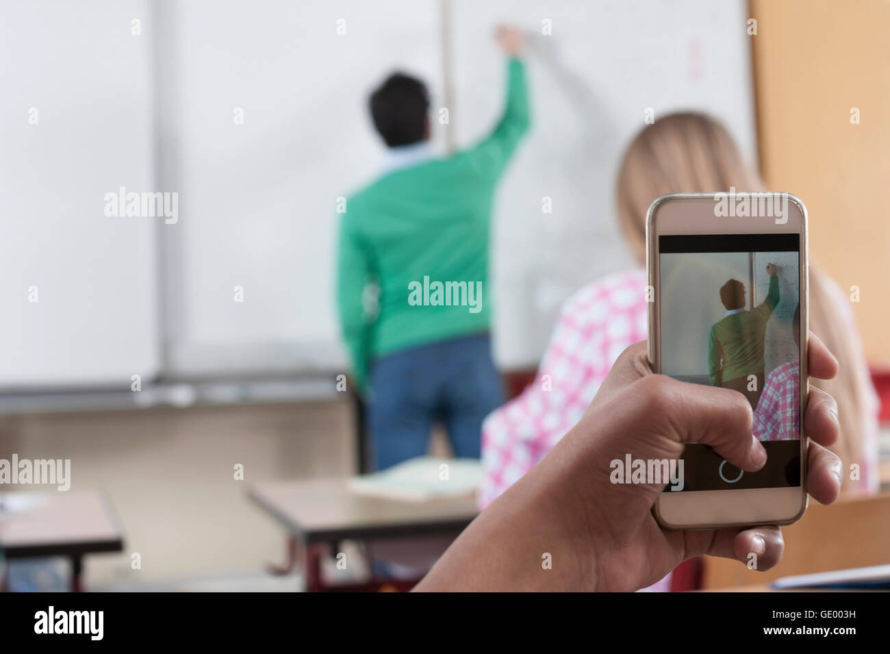 Lehrer Unterricht im Klassenzimmer während des Studiums nehmen sein Bild auf ihrem Smartphone, Bayern, Deutschland Stockfoto