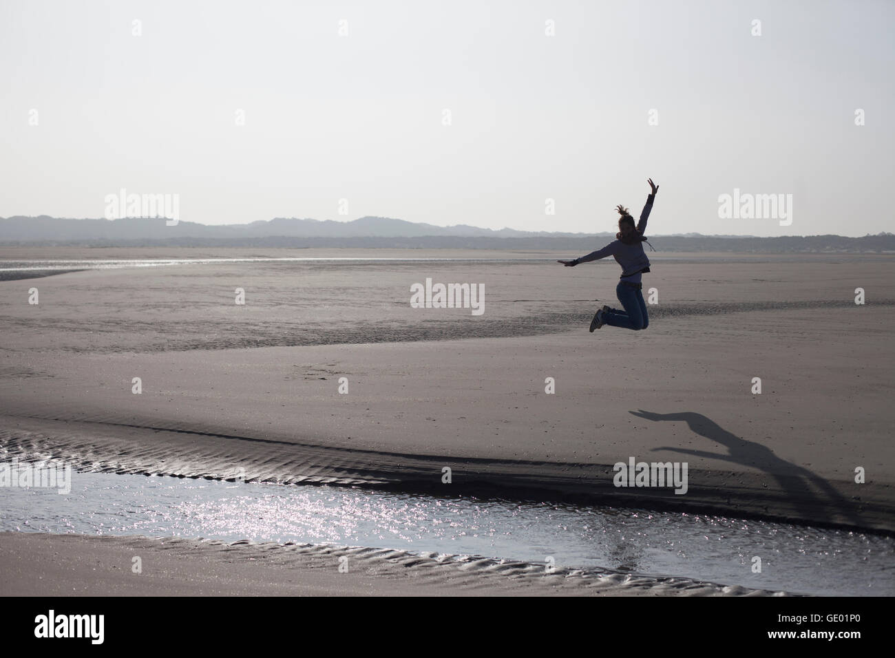 Mitte Erwachsene Frau springen in der Luft am Strand, Renesse, Schouwen-Duiveland, Zeeland, Niederlande Stockfoto