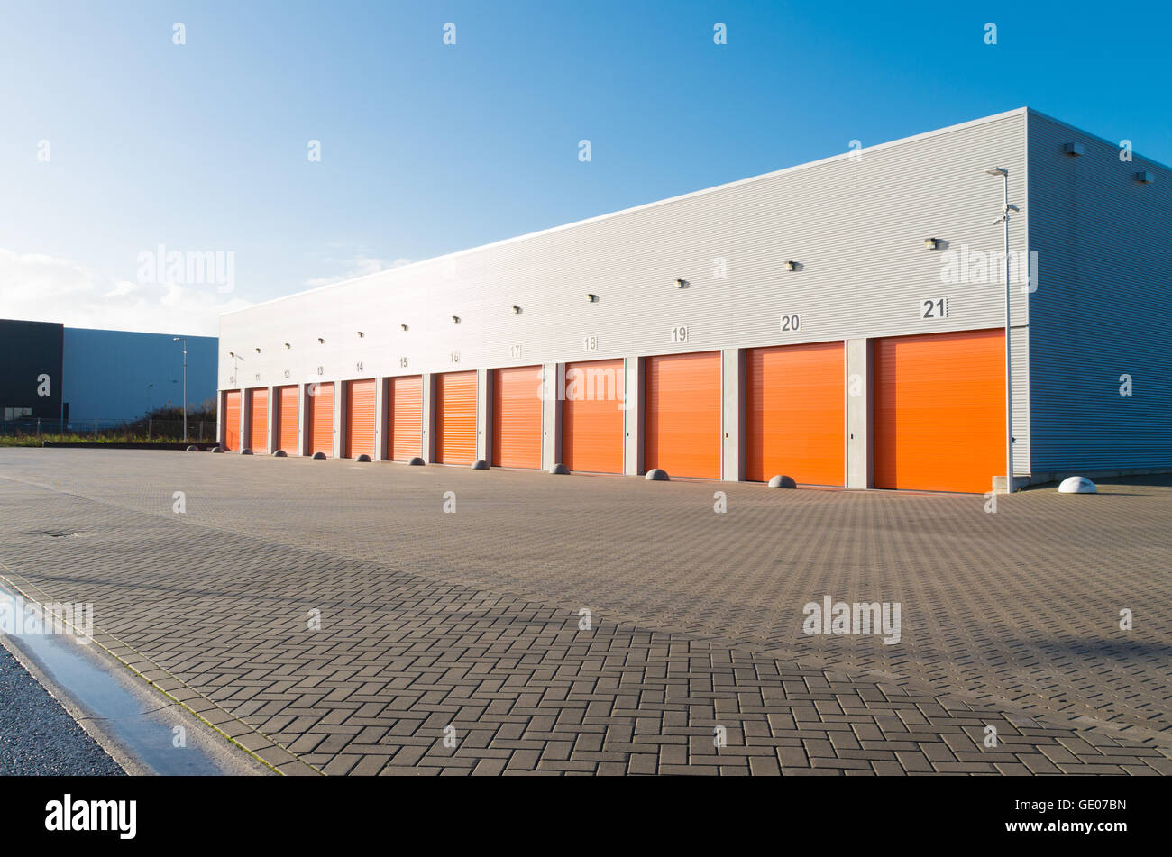 außen eine gewerbliche Lagerhalle mit orange Rolltore Stockfoto