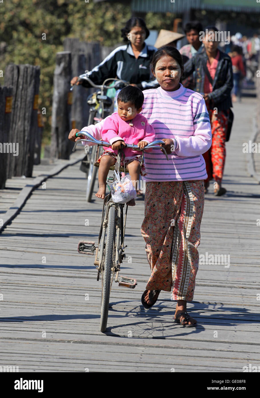 Frau mit Fahrrad und Kind zu Fuß auf der berühmten Teakholz Brücke (U Bein Brücke) in Mandalay. Stockfoto