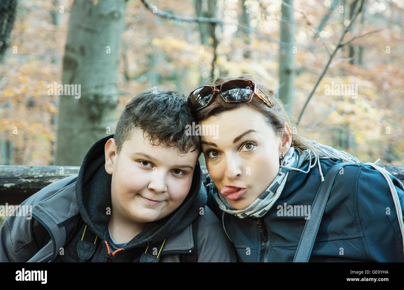 Verrückte Frau mit Sohn posieren in den herbstlichen Laubwald. Wandern-Thema. Saisonale natürliche Szene. Porträt von Reisenden. Stockfoto